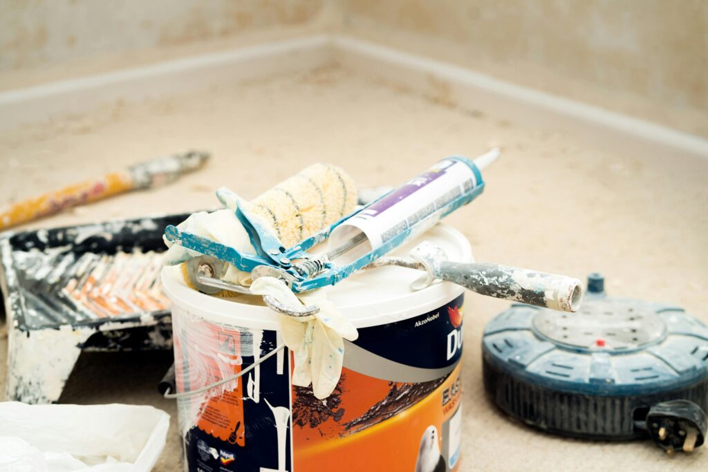 A collection of painting tools and materials for home renovation, featuring paint rollers and a bucket.
